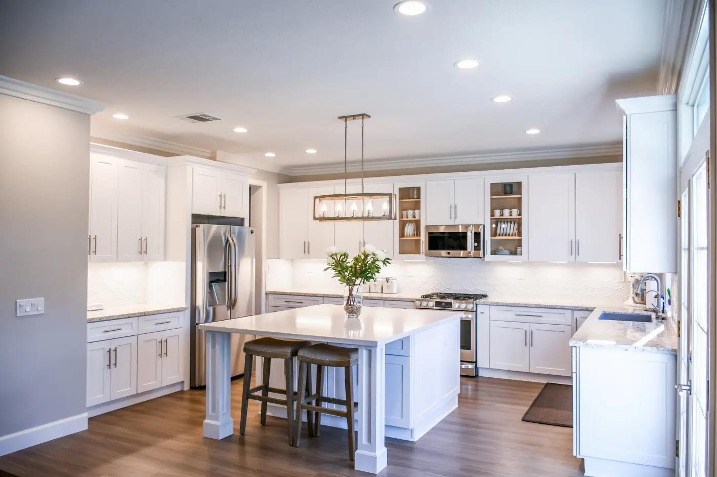 White kitchen with a large island, pendant lights and stainless appliances