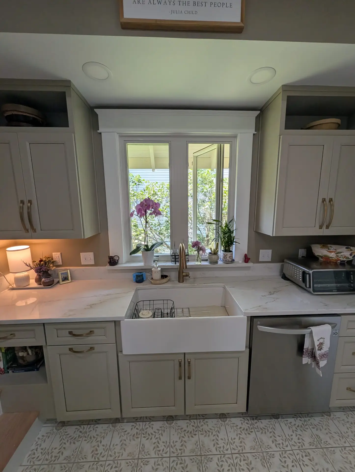 Kitchen brightened by a small addition, with a farmhouse sink under the window and gray cabinets