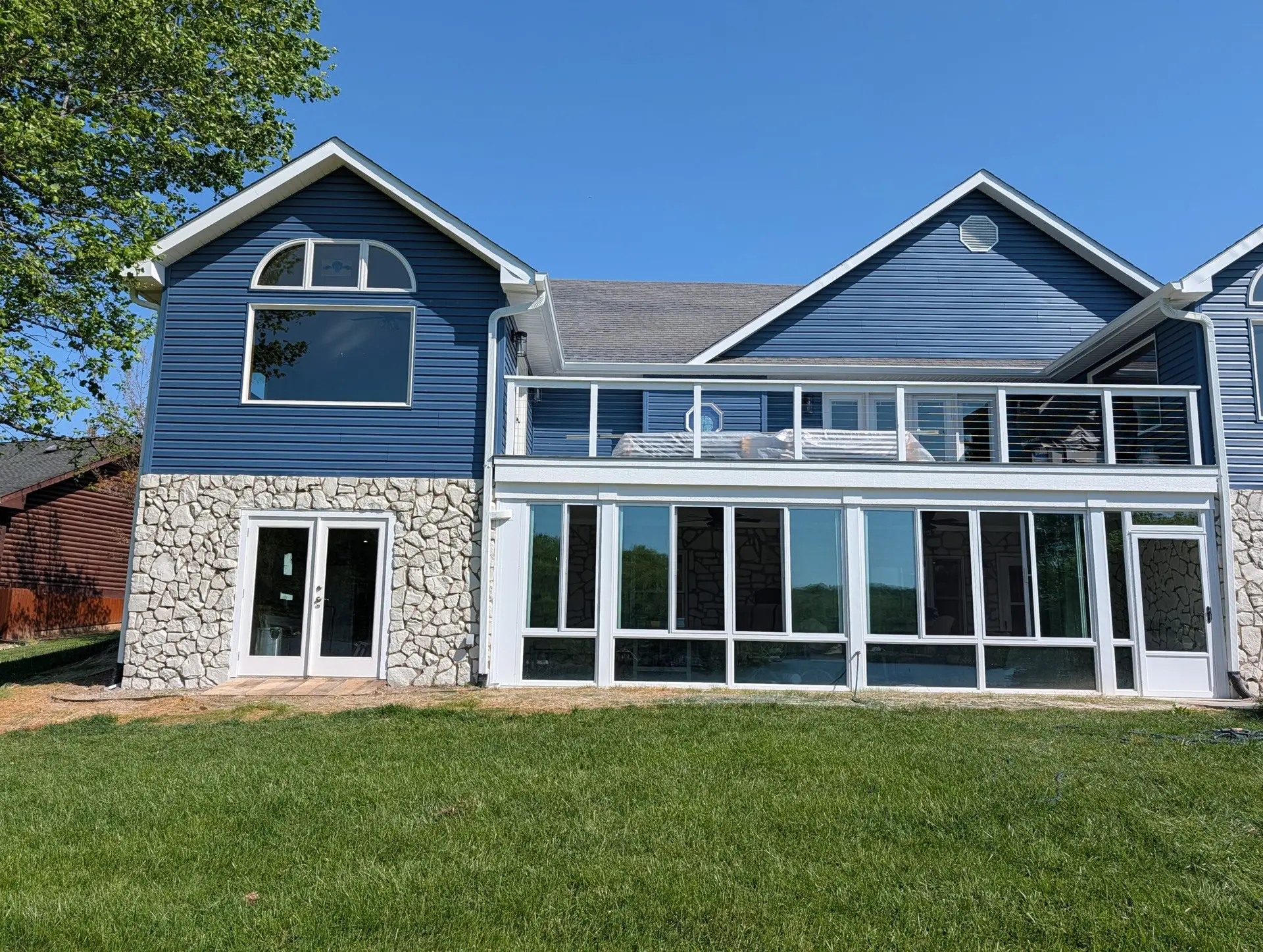 Rear view of a Martinsville lake home with two new gabled additions, full-width deck and glass sunroom